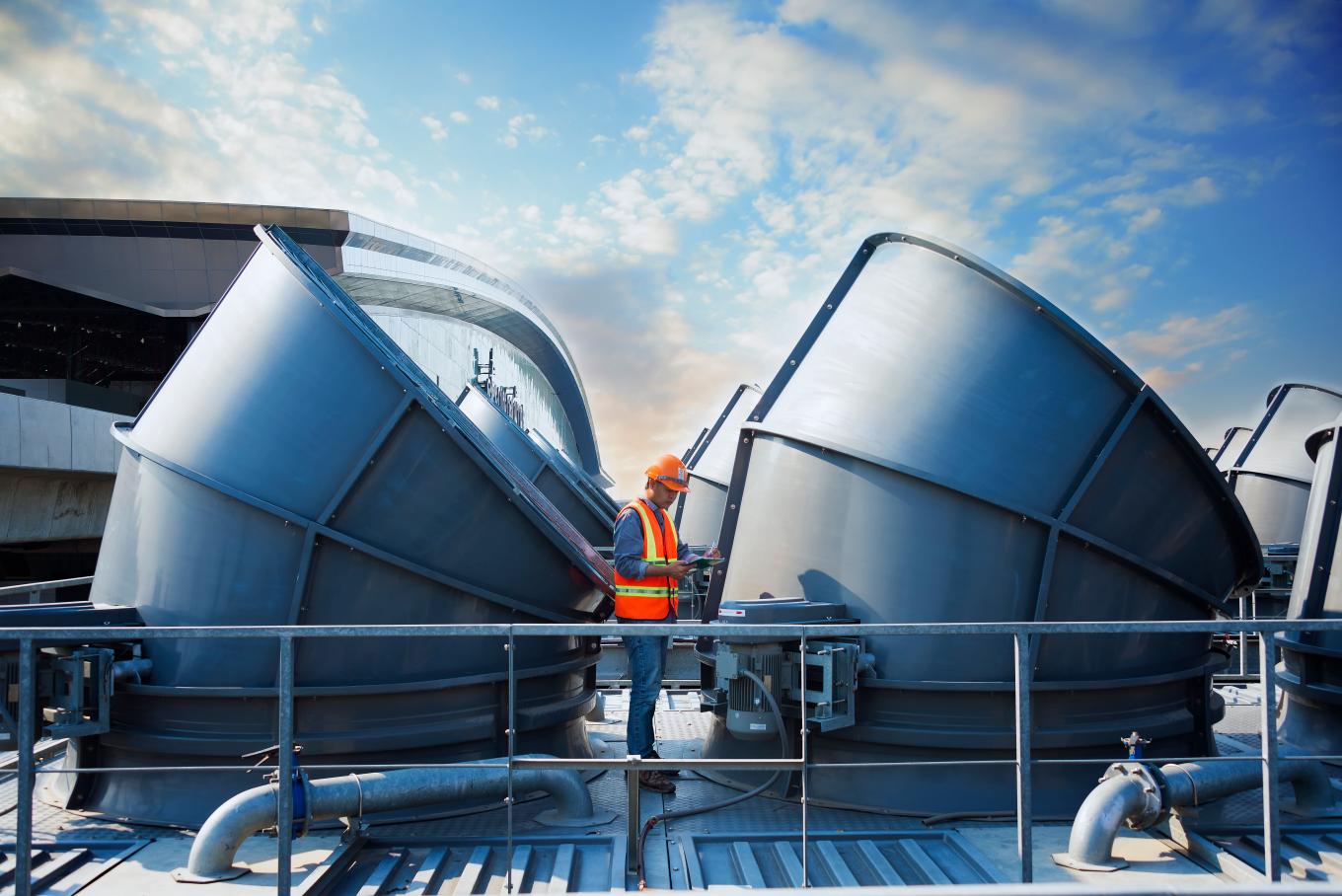 worker standing top of cooling tower on blue sky background